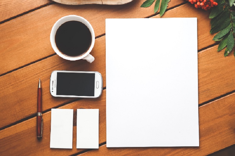 Coffee, cell phone, and blank pad of paper