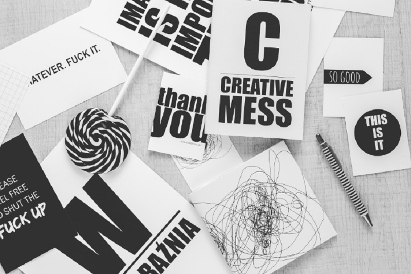 Messy desk strewn with paper and pens
